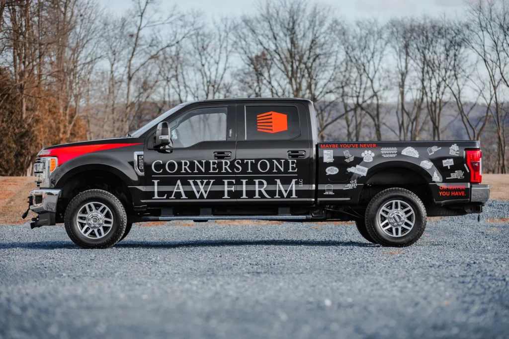 A photo of a black truck with a Cornerstone Law Firm wrap from the side