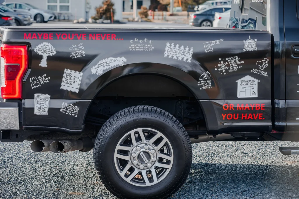 A photo of the back tire of a black truck with a Cornerstone Law Firm wrap