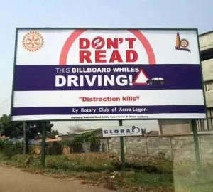 A complicated looking billboard that says "Don't Read This Billboard Whiles Driving. Distraction Kills"